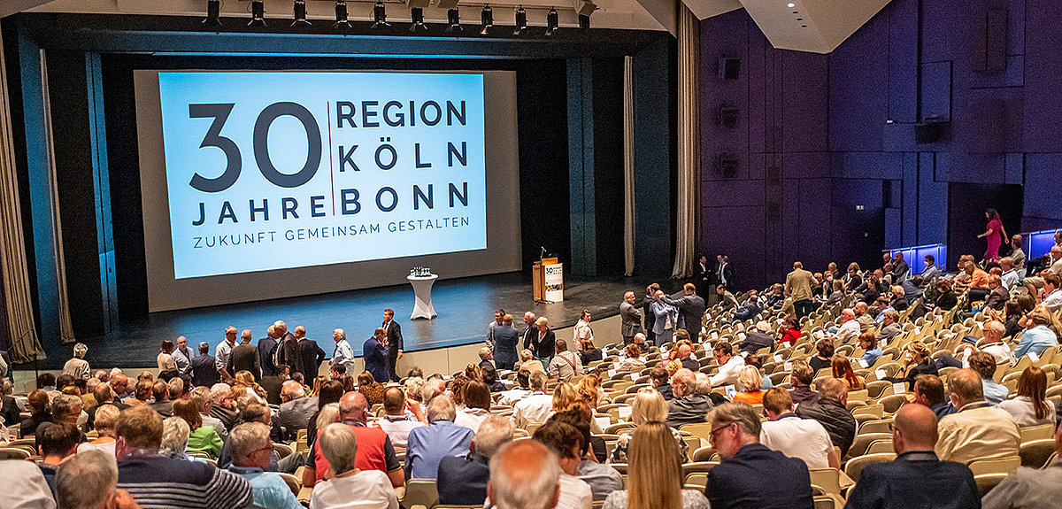Gäste des Langen Tages im Grpßen Saal des Forum Leverkusen. Auf der Leinwand das Jubiläumslogo des Region Köln/Bonn e.V.