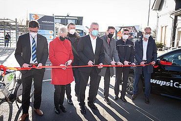 Sieben Personen, darunter Prof. Dr. Andreas Pinkwart, Wirtschaftsminister NRW, Stephan Santelmann, Landrat Rheinsch-Bergischer Kreis und Marion Lück, Bürgermeisterin der Stadt Wermelskirche, scheniden ein roten Band durch. Im Hintergrund sind teile des Bahnhofs von Wermelskirchen zu sehen. 