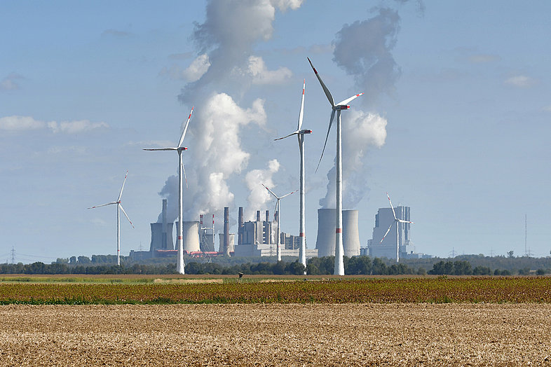 Windräder auf einem Feld in Bedburg und im Hintergrund das Braunkohlekraftwerk Neurath