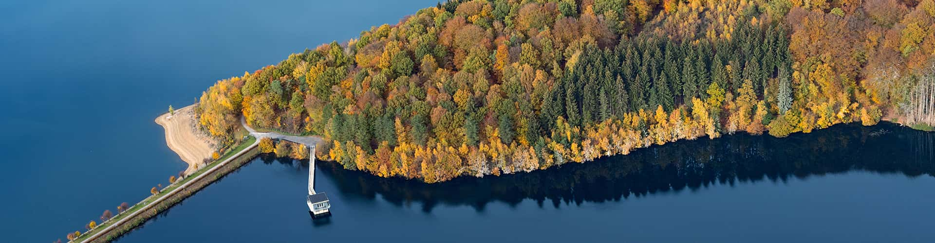 Ausschnitt der Dhünntalsperre mit See, Ufer, Wald, Damm und Häuschen auf dem Seh.